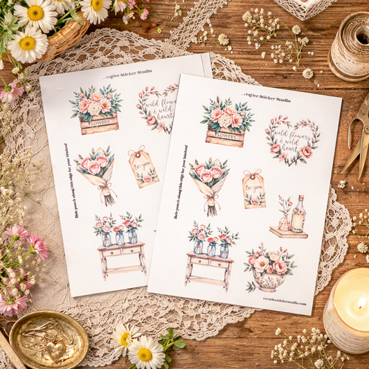 Floral-themed sticker sheets on a wooden surface with lace and flowers.