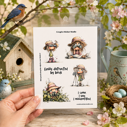 A hand holds a clear plastic package containing four illustrated stickers from Creative Sticker Studio. The package features whimsical bird-themed cartoon characters in hats and goggles, with text including 'Easily distracted by birds' and 'I came.