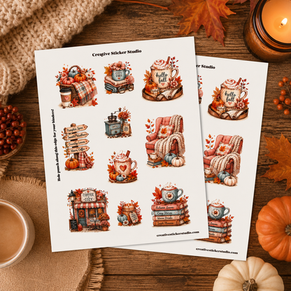 Two printed sticker sheets with autumn-themed illustrations, including mugs, pumpkins, fall leaves, and cozy decor, arranged on a wooden surface with seasonal props like a candle, knit fabric, and small pumpkins.