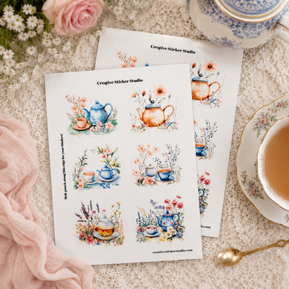 Two printed sticker sheets featuring watercolor tea and coffee cup illustrations, styled on a lace surface with a teacup, saucer, spoon, flowers, and a pink scarf. The sheets show the brand name 'Creative Sticker Studio'.